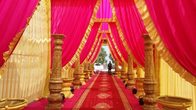 A magenta and gold drape passage with carved gold pillars over a red carpet